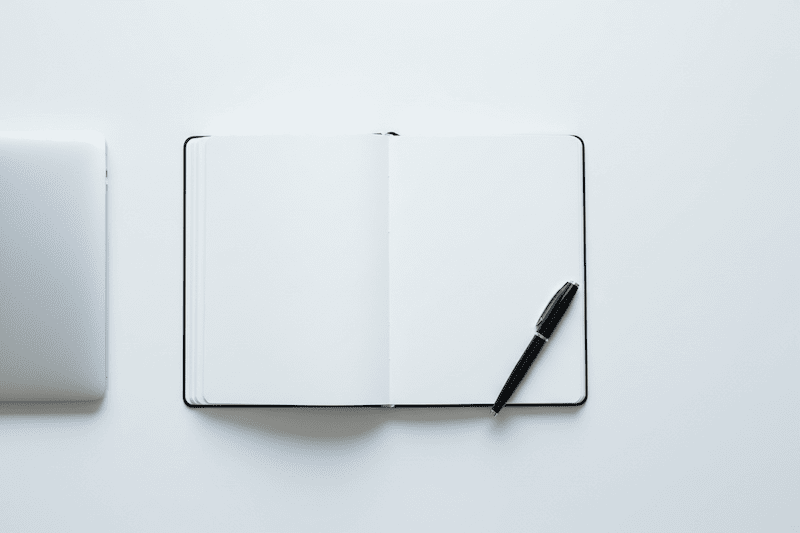 Money Mindset stärken: Minimalistischer Schreibtisch mit Erfolgsjournal und Laptop zur Planung finanzieller Ziele.